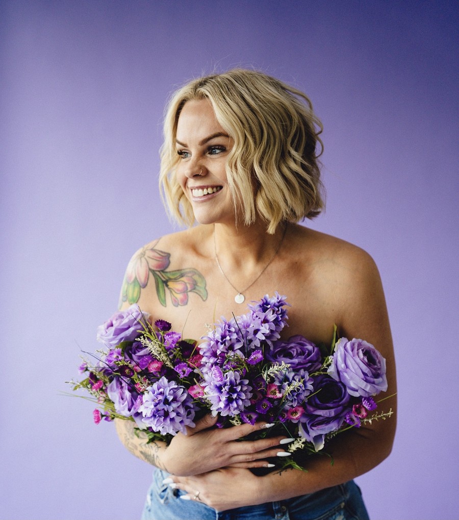 Heather smiling while holding a bouquet of purple flowers