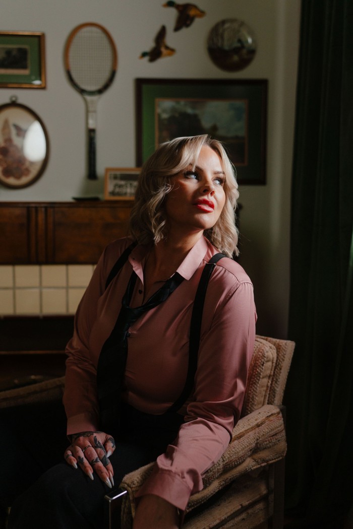 Heather seated in a pink shirt & black tie