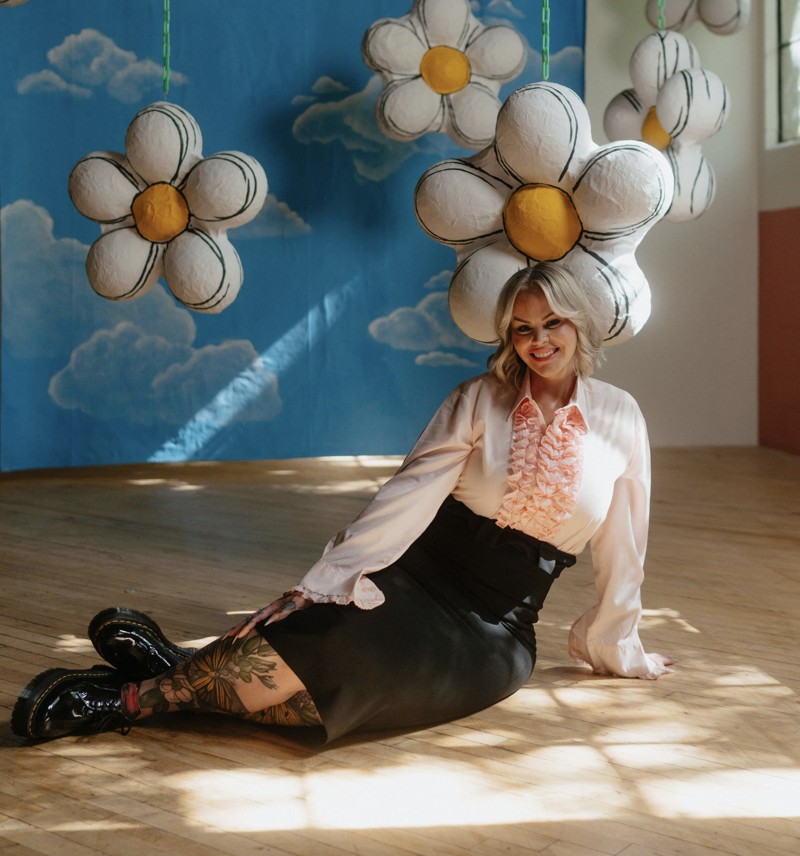 Heather smiling beneath hanging daisies